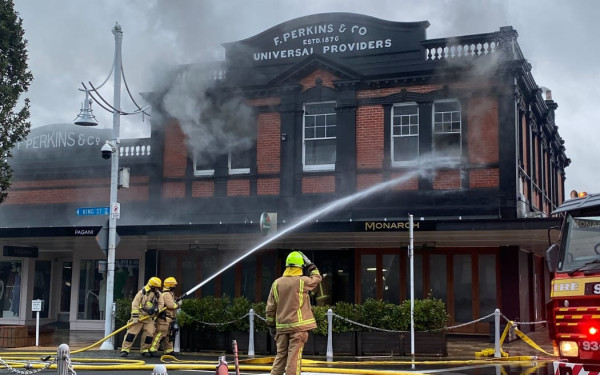 Volunteer firefighters facing the fire above the Monarch Restaurant on King Street in the historic Perkins Building